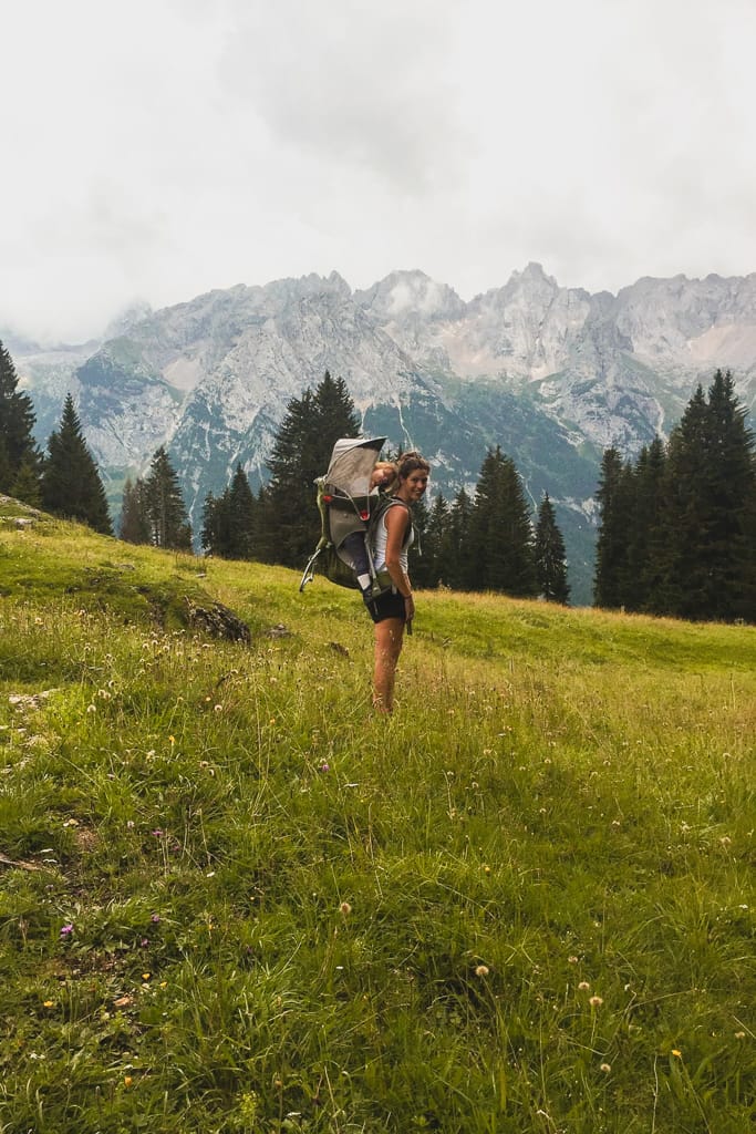 donna e mamma felice e sportiva con bambina sulle spalle nelle dolomiti tra la bellezza della natura