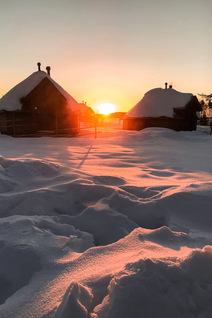 Alba magica all'Apukka Resort in Lapponia tra due casette immerse in un paesaggio innevato. Un richiamo alla mia passione per l’Artico e la sostenibilità