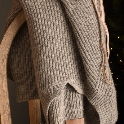 maglia calda per donna in pura alpaca realizzata eticamente appoggiata ad una slitta in un ambiente invernale
