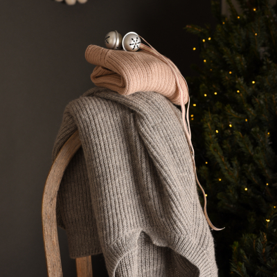 maglia calda per donna in pura alpaca realizzata eticamente appoggiata ad una slitta in un ambiente invernale