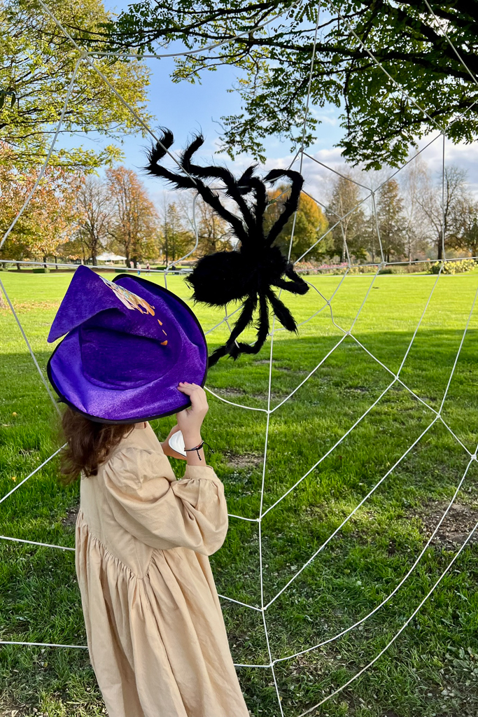 bambina elegante con cappello da strega all'arboretum di lubiana dove c'è una ragnatela gioco e un ragno da halloween